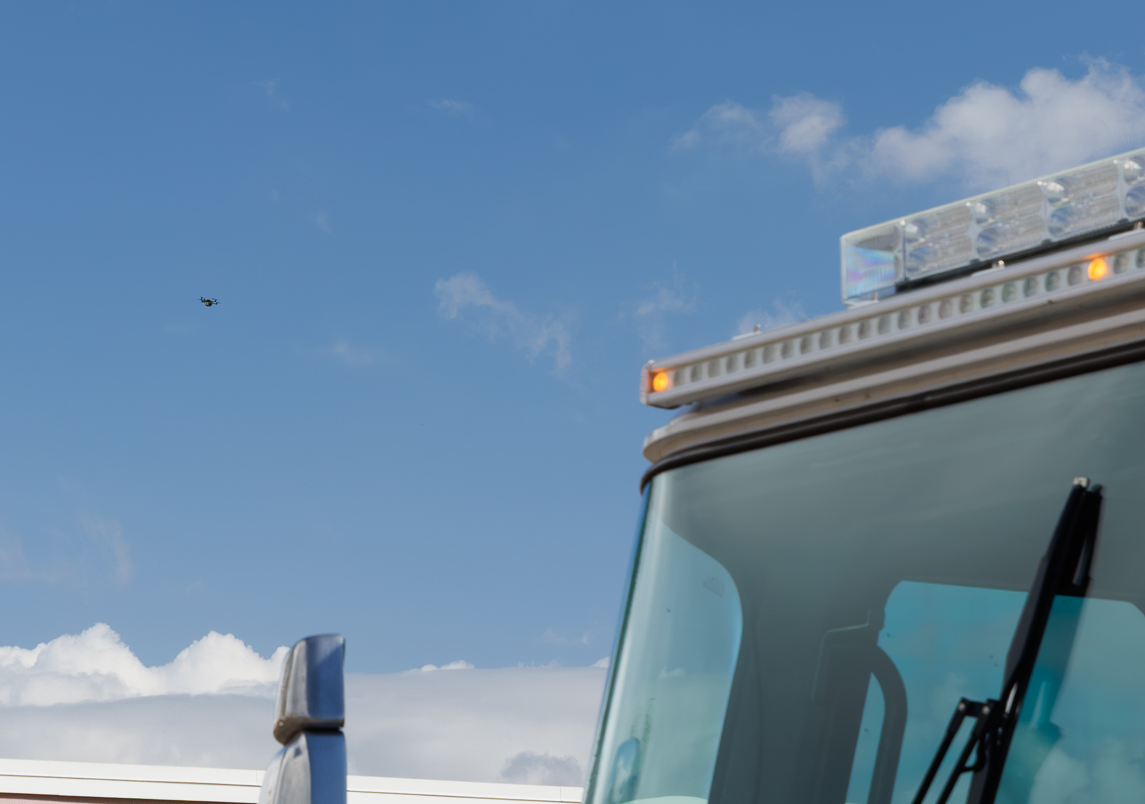 ArcherFRS aircraft in the sky above an emergency vehicle on scene